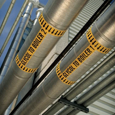 Yellow printed identification markers wrapped around industrial pipework